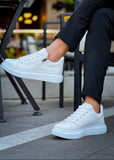 White sneakers worn by a person sitting outdoors.