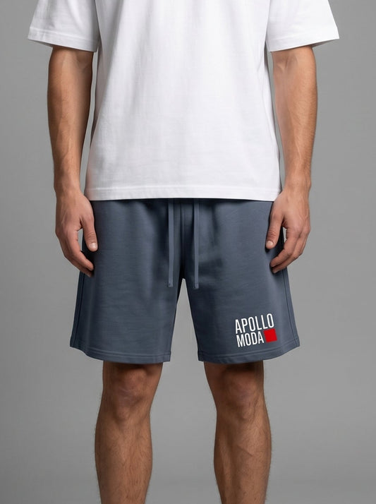Man wearing a white t-shirt and dark shorts with a logo on a gray background