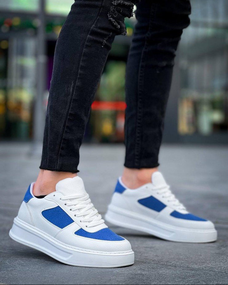 White sneakers with blue accents worn by a person on a blurred street background