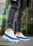 White sneakers with blue accents worn by a person on a blurred background