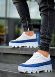 White sneakers with blue soles worn by a person on steps.