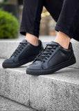 Black sneakers worn on a concrete step with a blurred background
