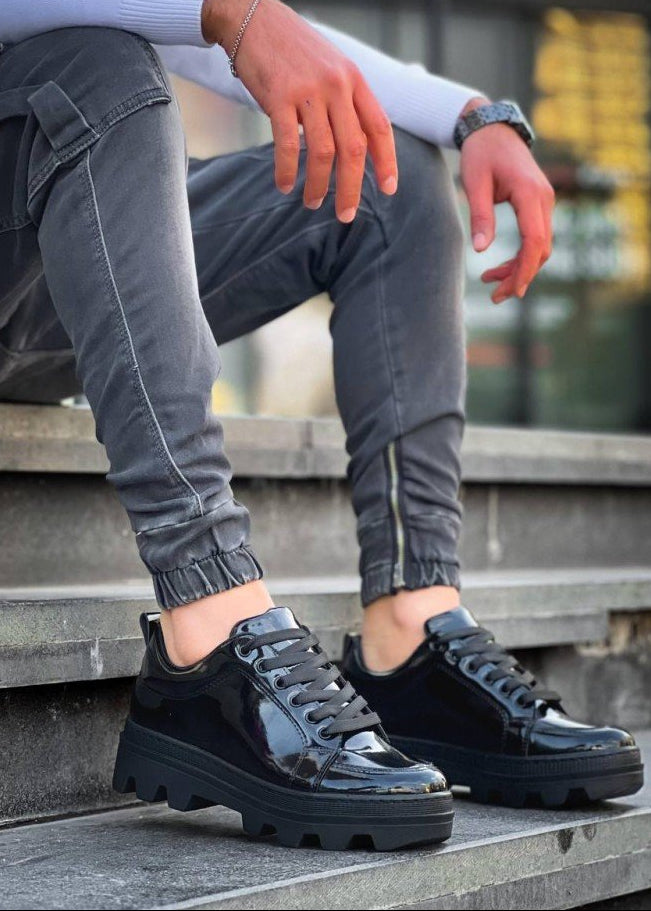 Black glossy shoes worn by a person sitting on steps.