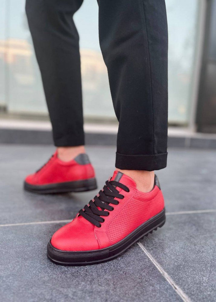 Red sneakers with black laces worn on a gray floor.