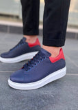 Navy blue sneakers with red accents worn by a person on a tiled floor.