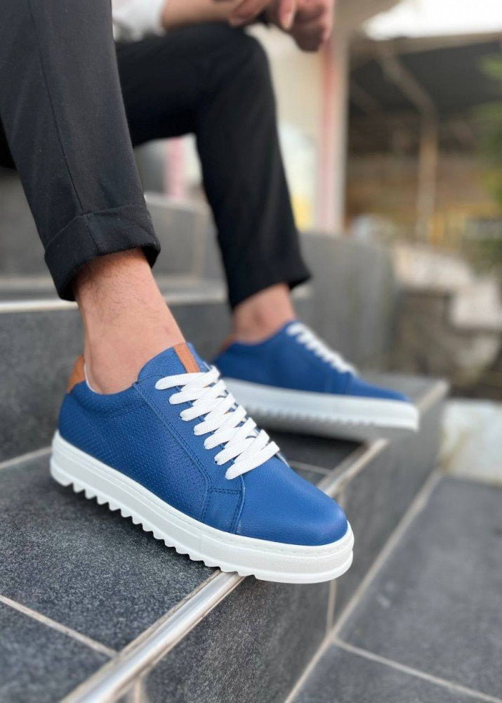 Blue sneakers with white soles worn on a step