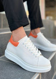 White sneakers with orange accents worn on a stone step.