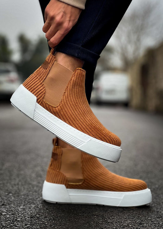 Brown Apollo Boots with white soles worn by a person on a blurred street background
