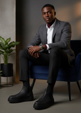 Man in a tailored grey suit wearing black Avalon Chelsea boots for a refined look.