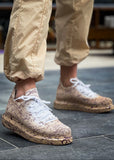 Man wearing Torino Light Brown Peak sneakers with hand-painted splatter design and white laces.