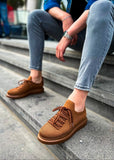 Brown shoes worn on a person's feet stepping down concrete stairs.