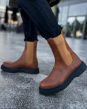 Brown leather Chelsea boots on a blurred street background