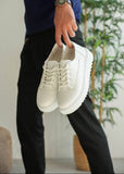 White sneakers held by a person with a blurred background