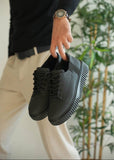 Person holding a pair of black sneakers with a blurred background